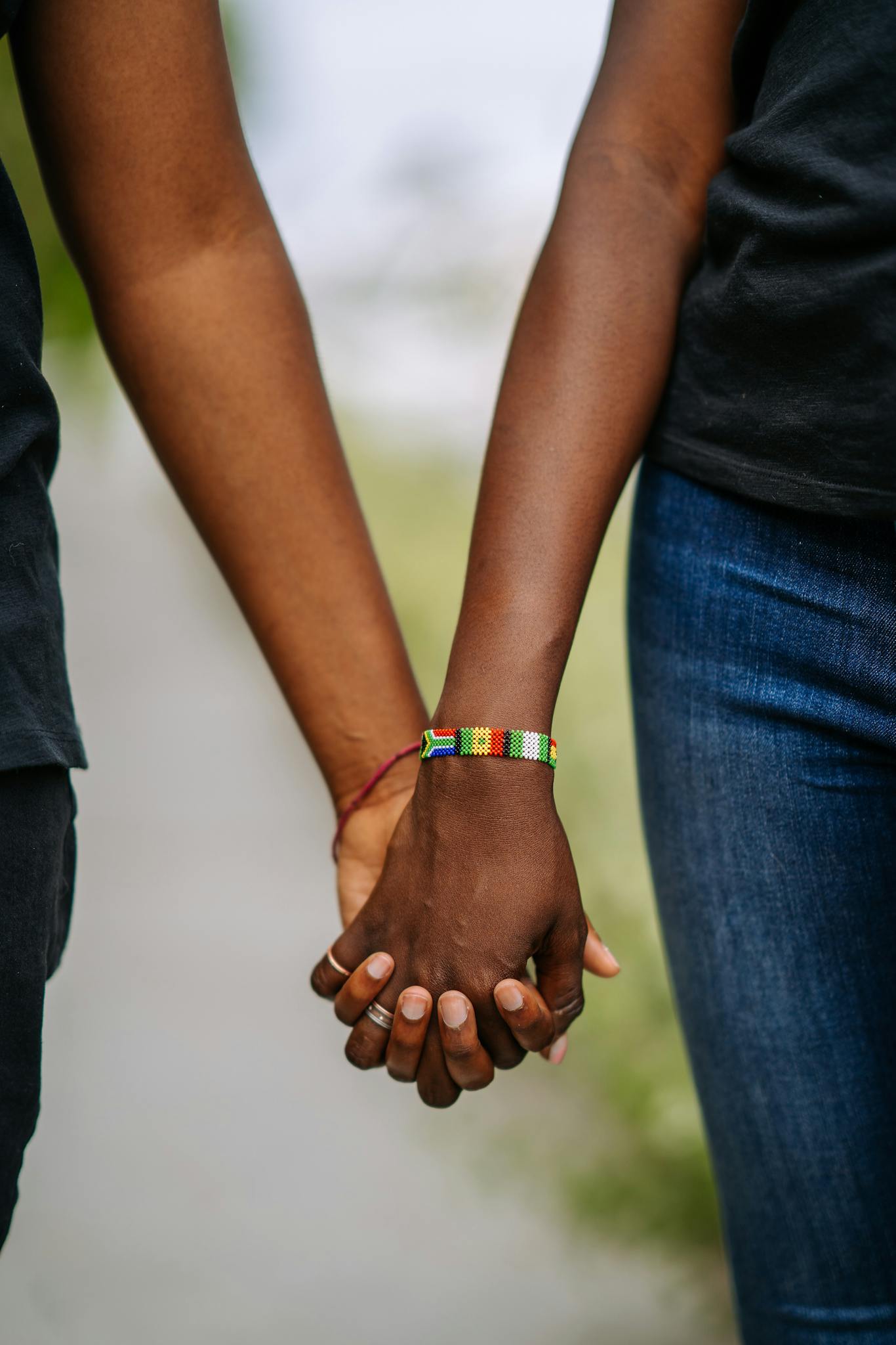 A close-up of two people holding hands outdoors, symbolizing connection and unity.