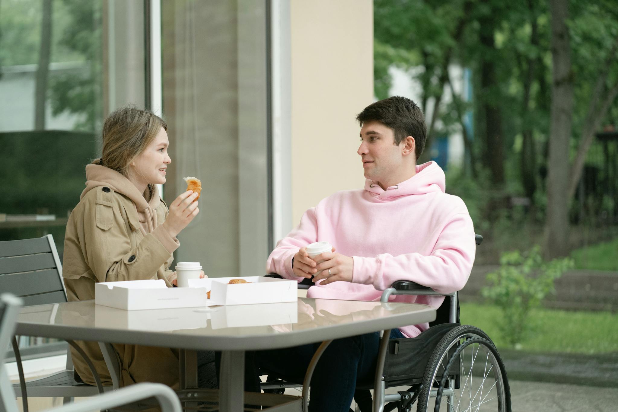 A young man and woman having a casual coffee date outdoors. Inclusive and warm atmosphere.